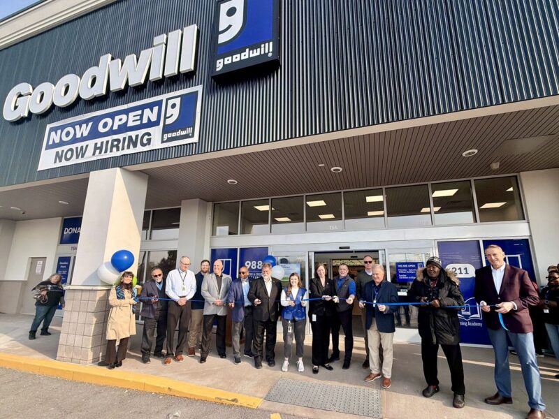 A group of people are gathered and posed to cut the ribbon for the new Goodwill location in Chili, NY.