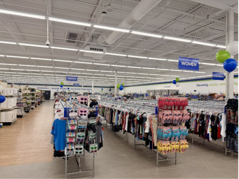 The interior of the Goodwill Chili location the day of its ribbon-cutting. Clothing items hang on racks under a sign that reads "WOMEN."